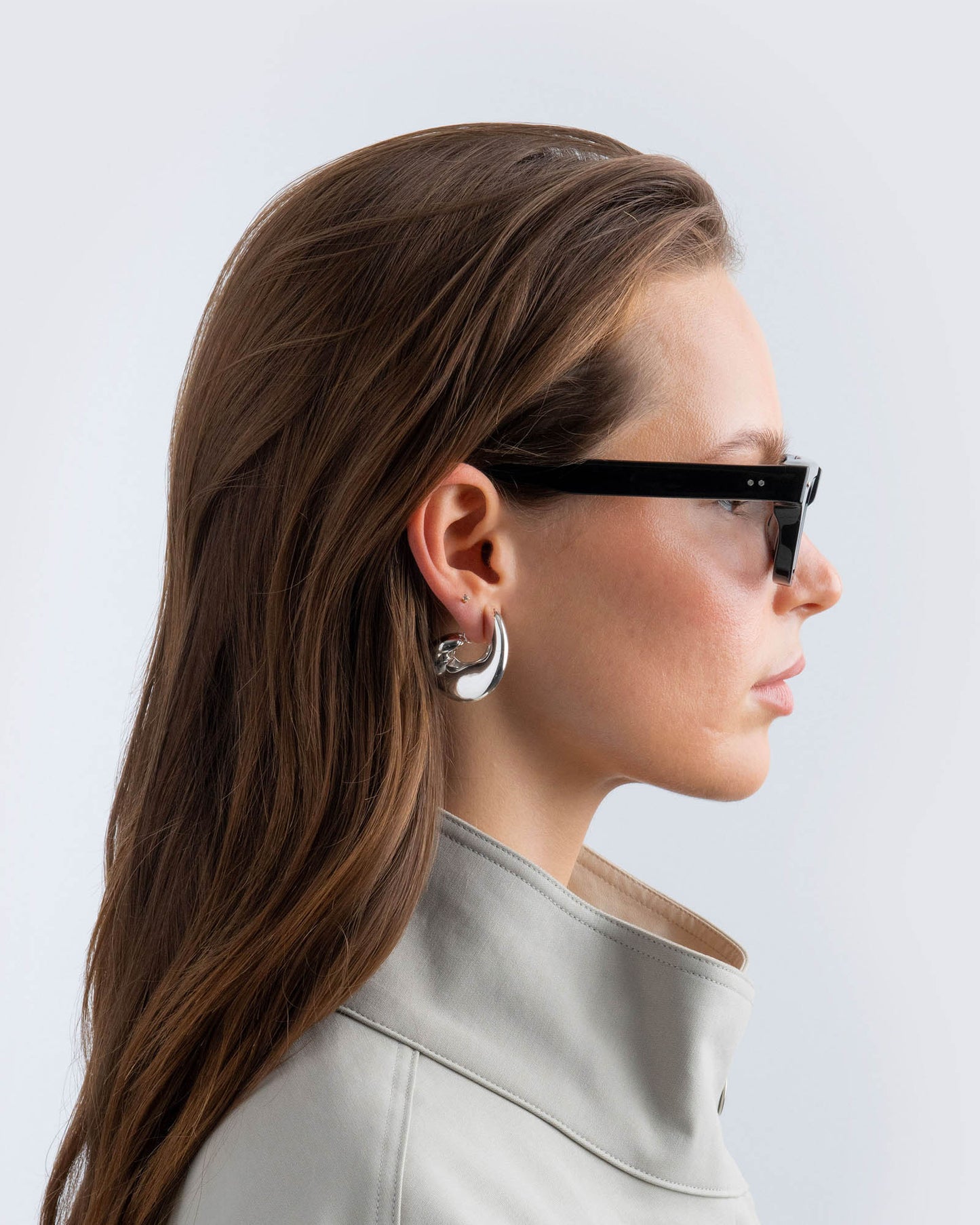 Woman wearing black sunglasses with grey lenses against a light background