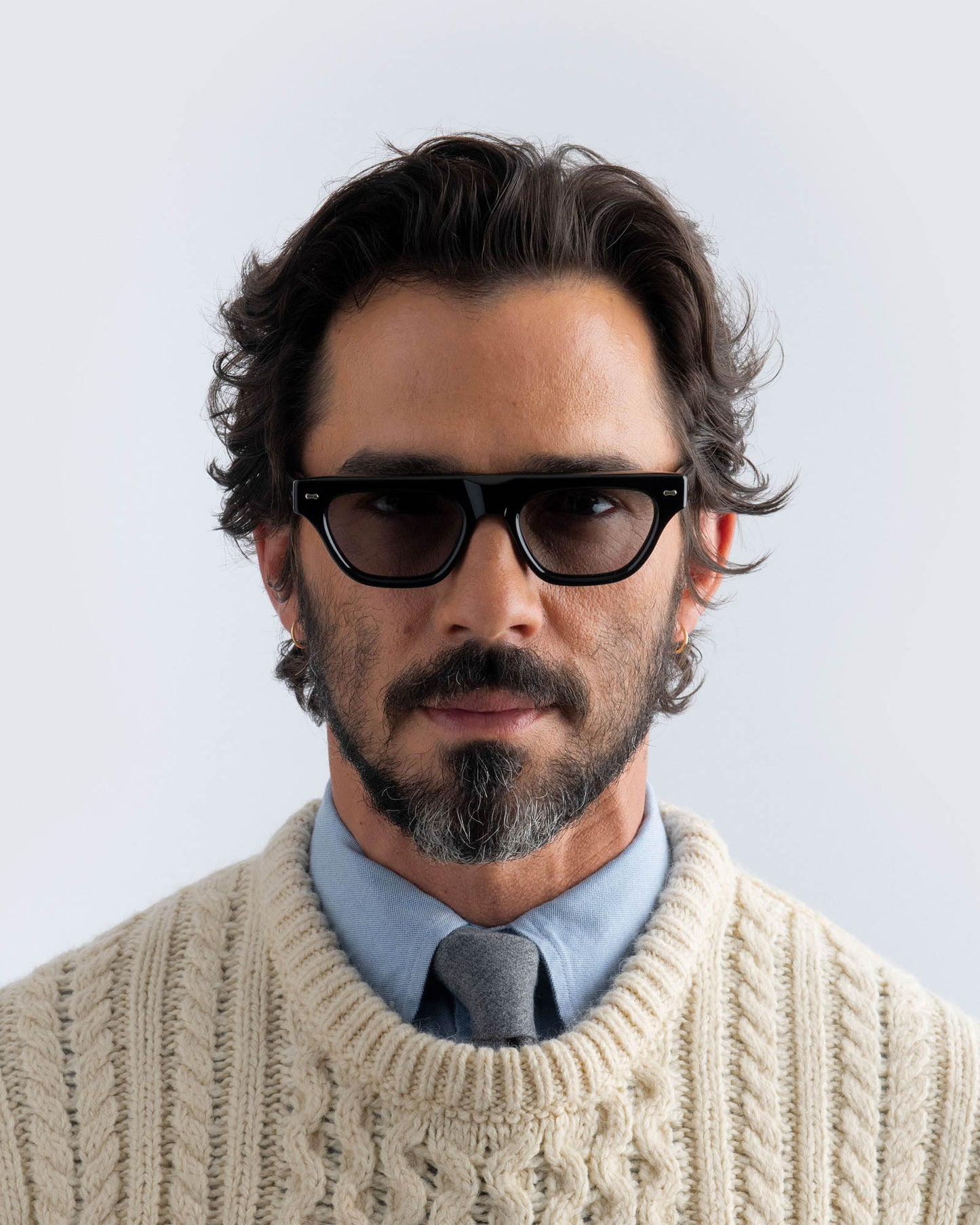 Man wearing black sunglasses with grey lenses against a light background