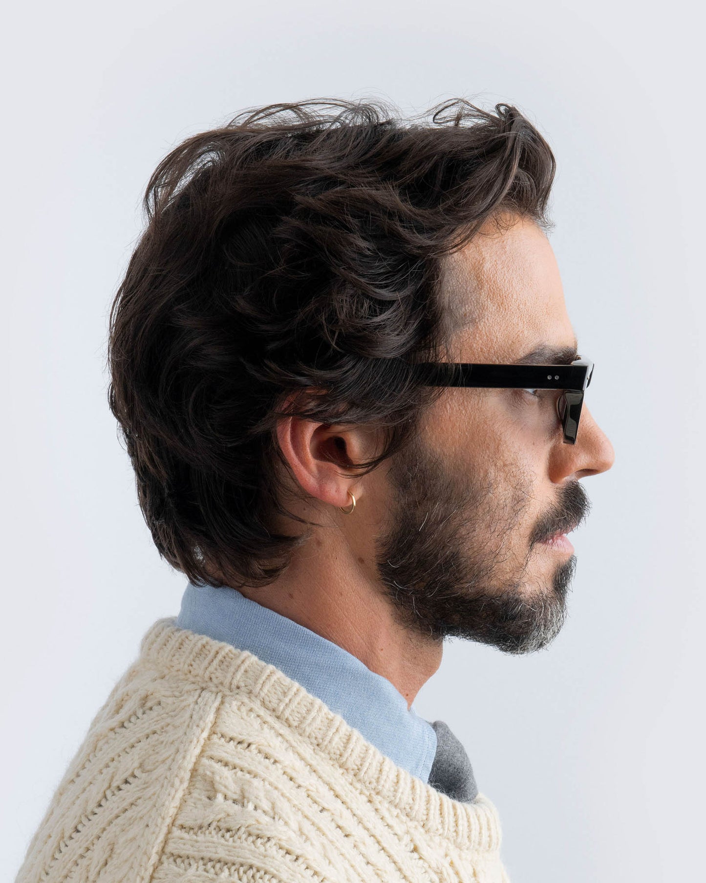 Man wearing black sunglasses with grey lenses against a light background