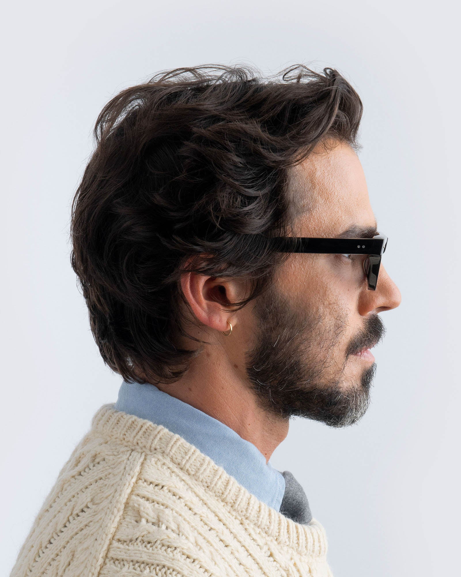 Man wearing black sunglasses with grey lenses against a light background