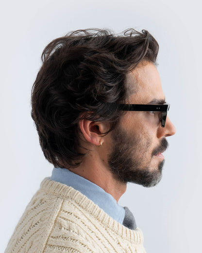 Man wearing black sunglasses with grey lenses against a light background