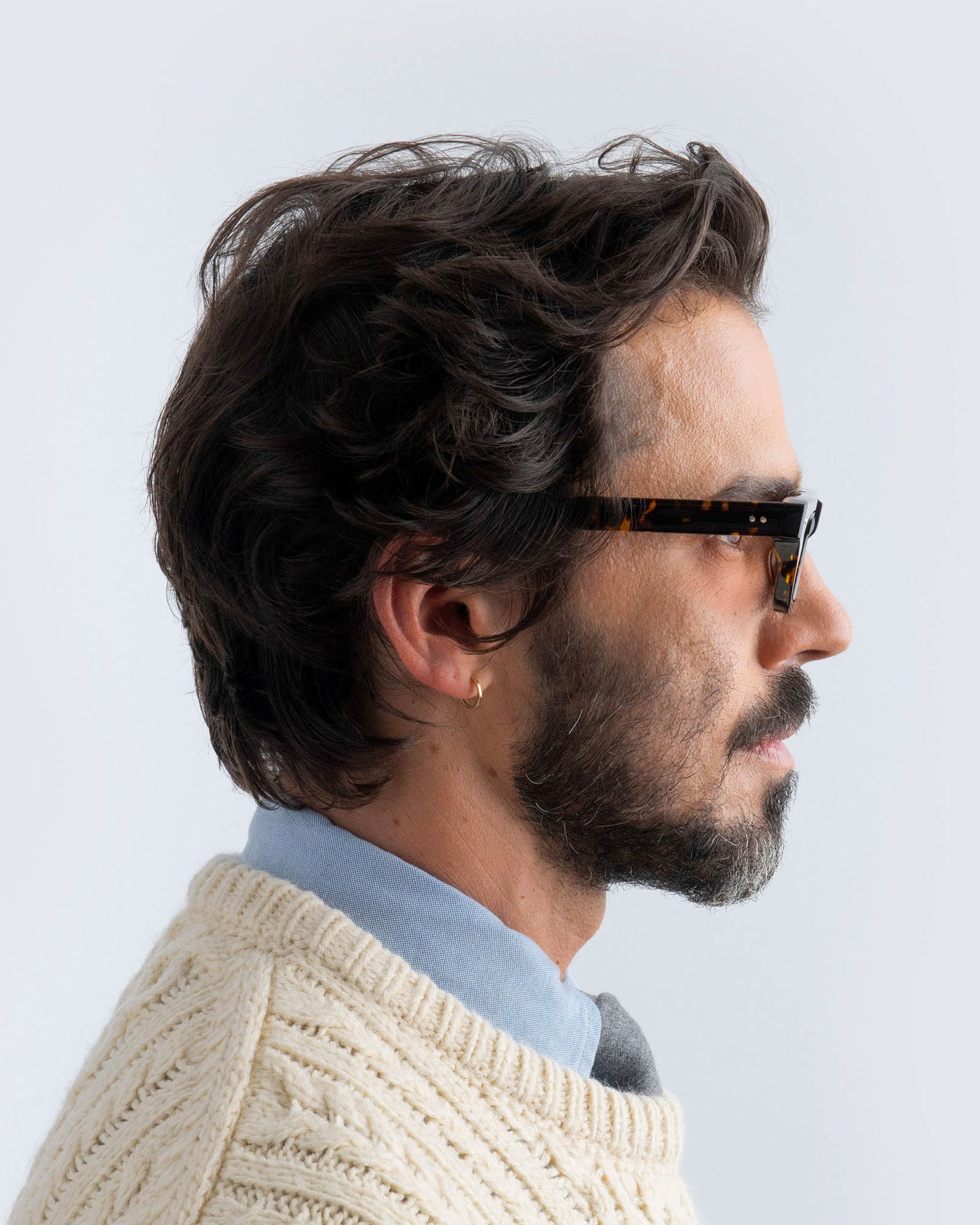 Woman wearing tortoiseshell sunglasses with brown lenses against a light background