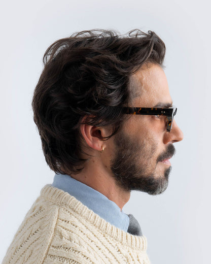 Woman wearing tortoiseshell sunglasses with brown lenses against a light background