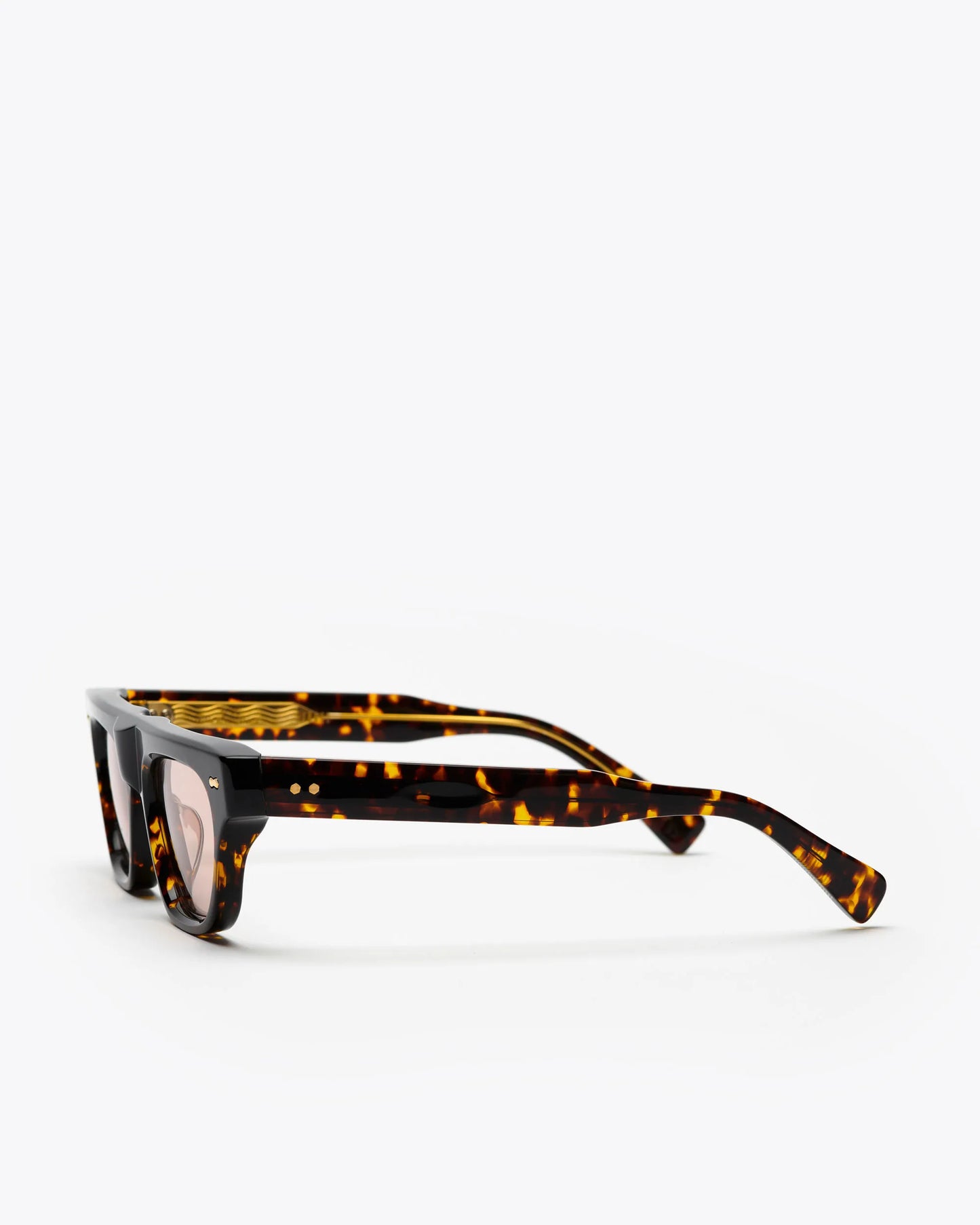 Cat-eye sunglasses with tortoiseshell frame and brown lenses, sideways, on a white background