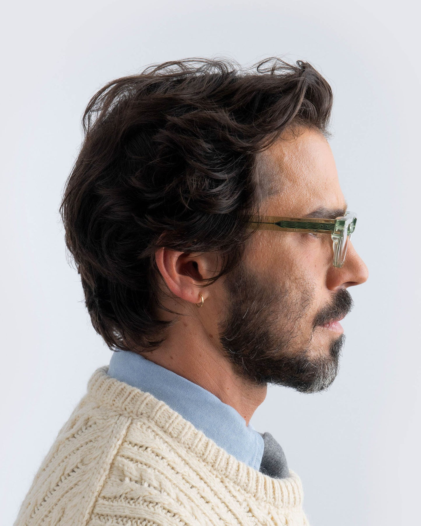 Man wearing seafoam green sunglasses with lilac lenses against a light background