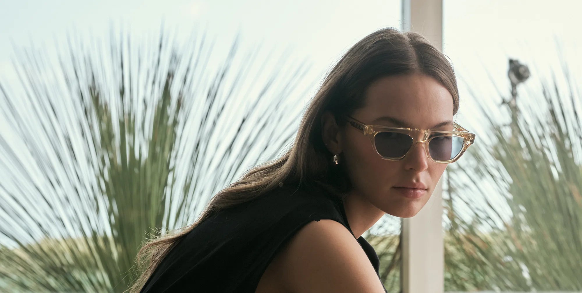 Woman wearing yellow sunglasses with blue lenses with a blurred natural background