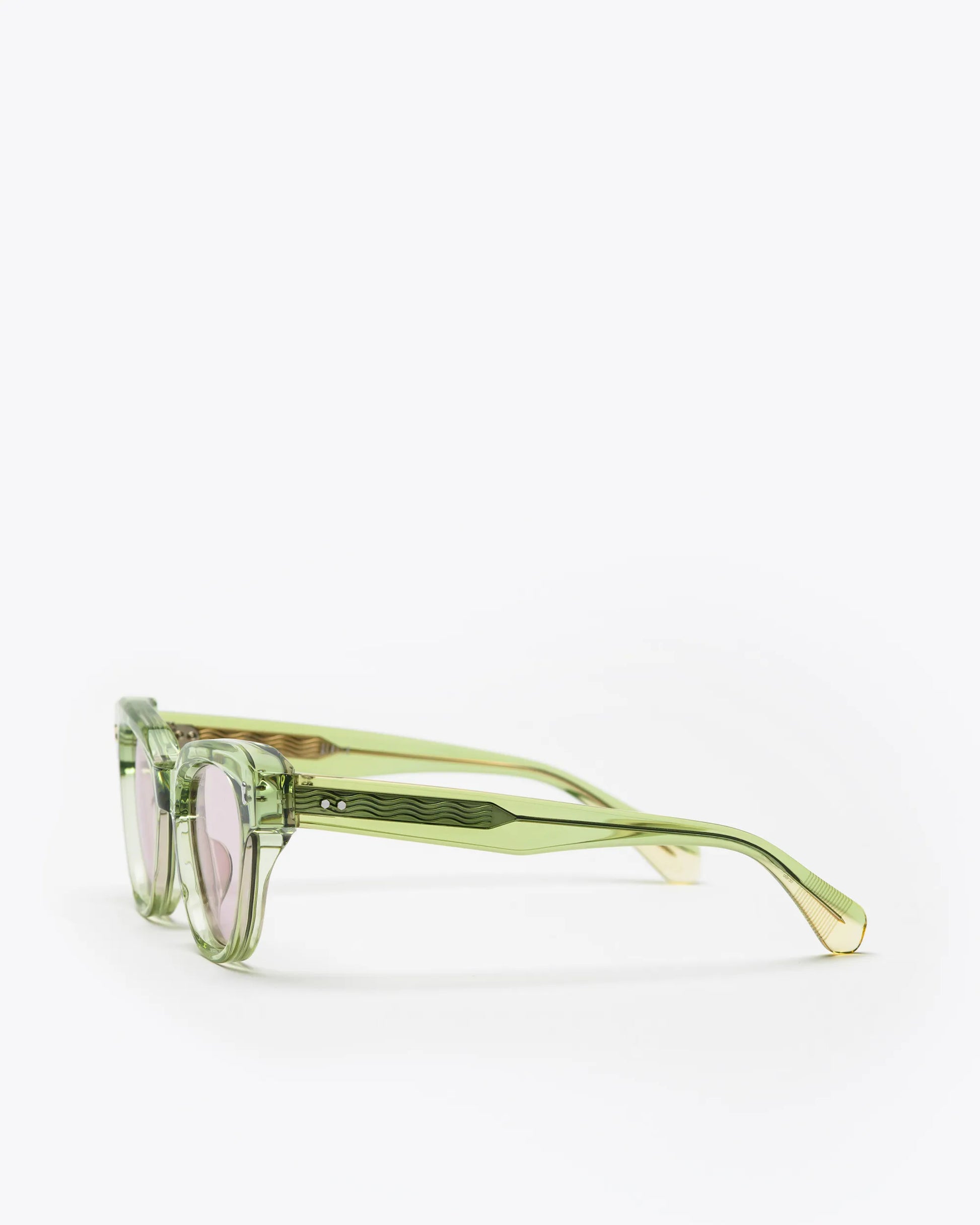 Seafoam green sunglasses with lilac lenses, sideways, on a white background