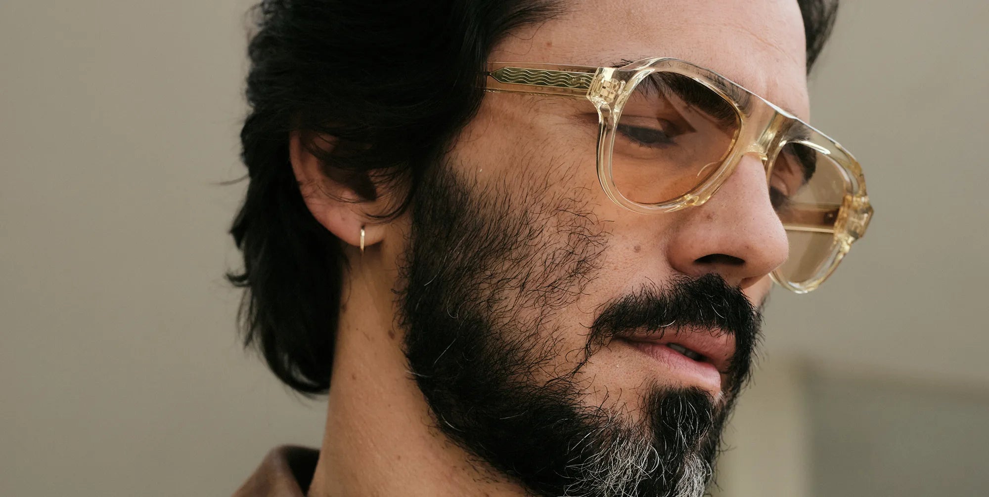 Man wearing champagne sunglasses with a neutral background